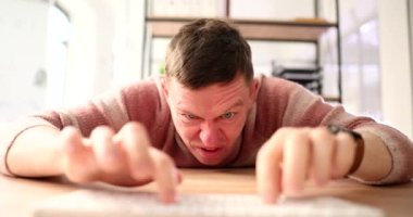 Bilgisayar klavyesinde yazı yazan ve internete 4K film yavaş çekim şikayeti yazan kızgın bir adam. İnternet dolandırıcılığı kavramı