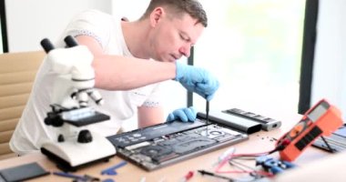 Usta tamirci atölyede dizüstü bilgisayarı tamir ederken tornavida 4K film yavaş çekimde. Garanti konsepti altında elektronik ürünlerin bakımı