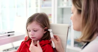 Doktor otorhinolaryngolog, klinik 4K filminde otoskoplu küçük bir kızın kulağını inceliyor. Çocuk konseptinde otitis medyasının teşhisi ve tedavisi ve işitme kaybı