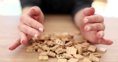 Eller masa dolusu ahşap küplerin üzerine alfabe yakın çekim 4K harfleri ve ağır çekim filmler dökülüyor. Masa oyunları konsepti