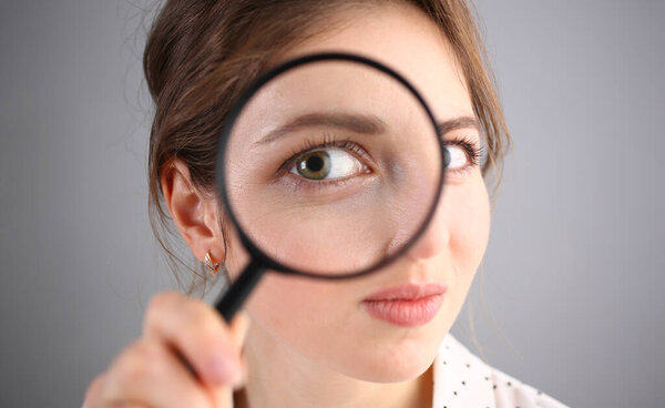 Inquisitive young woman looking through magnifying glass. Search for business ideas and new creative creative information