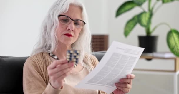 戴眼镜的老年妇女正在阅读4K片慢动作的说明书 老年人中药物的副作用概念 — 图库视频影像