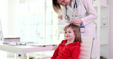 Klinikteki çocuk kızın saçlarını kontrol ediyorum. Doktor çocuk kılı varlığını kontrol ediyor. Pediküloz, bit salgını olabilir.