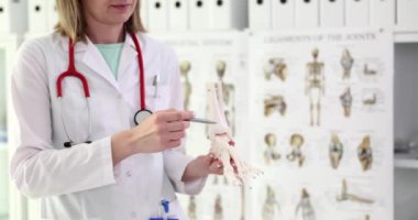 Ortopedi doktoru klinikte insan ayağı iskeleti tutuyor. Kemik erimesi kronik olarak iskelet ve bacak hastalığıdır.