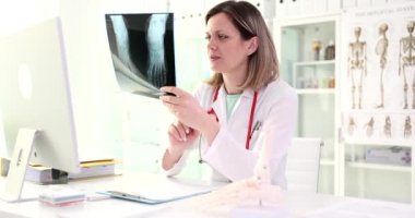 Doktor ayak röntgeni ve bacak kemiklerinin anatomisini tutuyor. Düz taban sebep olur ve belirtiler