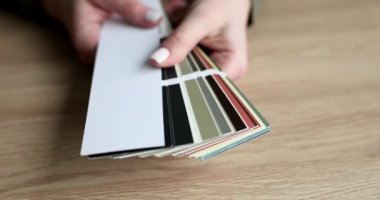 Kadın eli, renk örneklerini masanın üstünde tutuyor. Grafik tasarımcısı veya istemci katalog rengini seçer