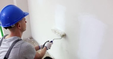 Duvarı beyaza boyayan profesyonel bir ressam. Duvarları silindirle boyamak ve tamir ve yeniden yapılandırma konsepti