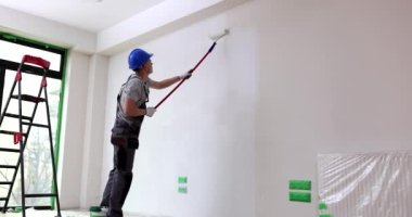 İnşaat alanında duvarları silindirle boyayan biri. Kaliteli hizmetler, boyama ve sıva işleri