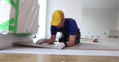 Erkek tamirci, doğal ahşap lifinden açık renkli lamine döşüyor. Fiberboard substratında zemin kurulumu