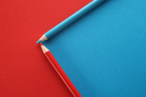 Blue and red pencils on red and blue background. Colored pencils on background of opposite colors