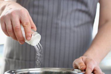 Aşçının elleri mutfaktaki tencerede suyu tuzlar. Yemek konseptinde tuz tozu