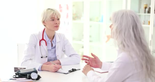 Arzt Therapeut Kommuniziert Mit Älteren Patientin Und Schreibt Beschwerden Krankengeschichte — Stockvideo