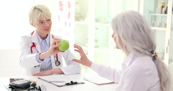 Γιατρός Θεραπευτής Δίνει Πράσινο Μήλο Ηλικιωμένη Γυναίκα Ασθενή Στην Κλινική — Αρχείο Βίντεο