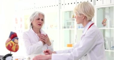 Yaşlı kadın hasta, 4K filminde kalp ağrısından doktora şikâyet ediyor. Yaşlılar konseptinde iskemik kalp rahatsızlığı belirtileri