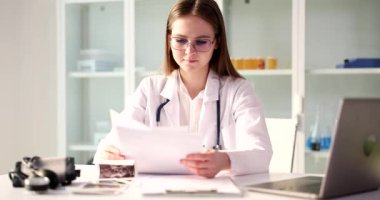 Genç bir kadın masadaki bir doktor yakın plan bir belgeyi izliyor. Tıbbi muayenenin sonucu