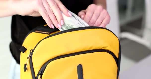 一只小巧 年轻的女手把美元放进一只黄色的背包里 探险准备工作 — 图库视频影像