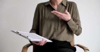 Dosyası olan bir iş kadını el kol hareketi diyor, yakın plan. Bireysel eğitim, eğitim