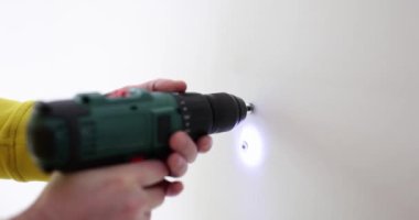 İnşaatçının elleri duvarda tornavidayla bir delik açıyor, yakın plan. Konsept apartman yenileme