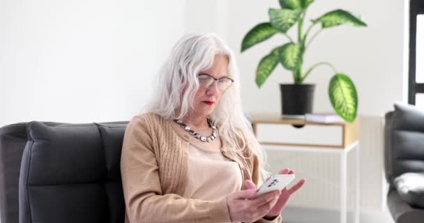 上了年纪的女人 头发灰白 戴着眼镜 在家里拨手机号4K电影慢镜头 打电话给父母的概念 — 图库视频影像