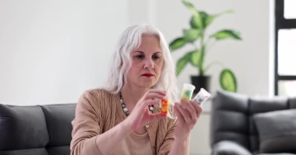 Starsza Kobieta Siwymi Włosami Patrząca Słoiki Lekami Domu Czytająca Tytuł — Wideo stockowe