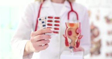 Doktor proktolojist elinde haplarla kabarcıklar tutuyor ve anatomik model rektum kapanış filmi ağır çekim. Basur ve rektal çatlakların tedavisi kavramı