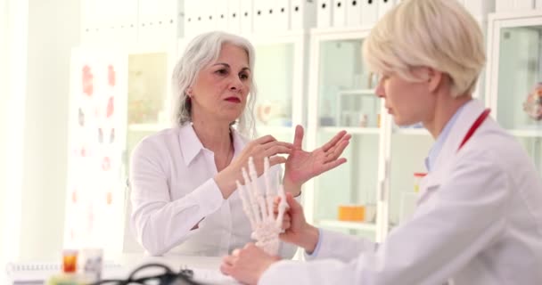 Lékař Revmatolog Ukazuje Anatomický Model Lidské Ruky Starší Ženy Revmatoidní — Stock video