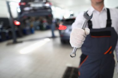 Üniformalı tamirci araba atölyesinde ingiliz anahtarı tutuyor. Araba servisi kavramı ve otomatik servis