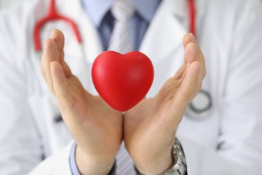 Doktor kardiyolog kırmızı kalbi havada tutuyor. Kalp nakli ve kalp damar hastalıkları