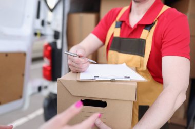 Kurye, teslimat makbuzunu imzalaması için müşteriye kalem verir. Teslimat servisi konseptinden bir paket al