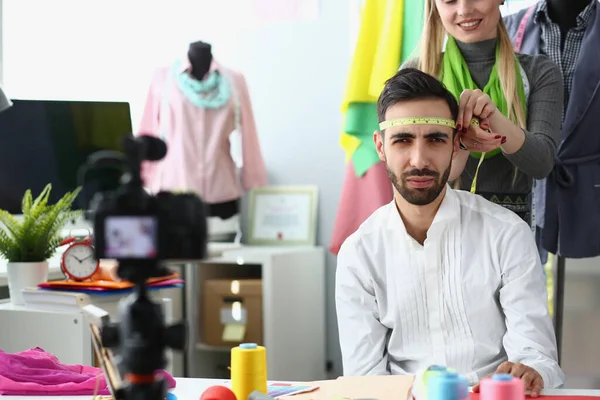 stock image Woman seamstress stylist jokes and measures head of a male designer with centimeter. Creative workshop and creative tailoring ideas