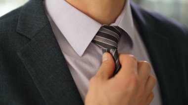 Takım elbiseli şık bir işadamı gömleği yakın çekimde düzeltiyor. Tarz sahibi erkek imajı iş stili kavramı