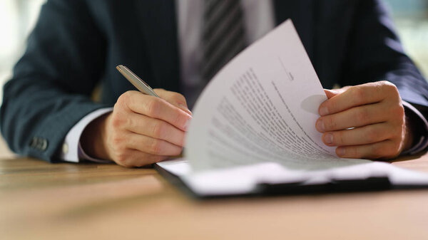 Businessman leafing through documents and signing contract for business deal at work in office closeup. Certification of documentation and control concept