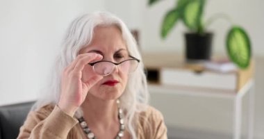 Düşünceli son sınıf öğrencisi kadın, oturma odasında ağır çekimde bir şeyler görebilmek için bardakları ayarlıyor. Görme sorunu tedavisi. Görüntü iyileştirme için suç ortağı