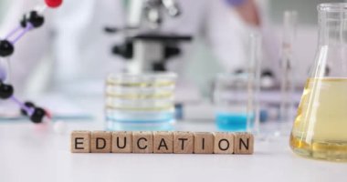 Modern laboratuvarda, beyaz masadaki tahta küplerden yapılmış kelime eğitimi. Sıvı örnekleriyle dolu mataralar ve tüpler laboratuarda incelenmeye hazır.