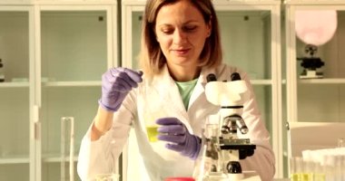 Dikkatli bir kadın mikroskop altında incelemek için sarı sıvı numunesi alır. Üniforma uzmanı kadın. Laboratuvarda hasta idrar testi yapıyor. Ağır çekimde oturuyor.