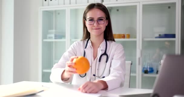 Pozitivní Doktorka Drží Zralou Oranžovou Ruce Dívá Kamery Lehce Usmívá — Stock video