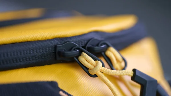 Zip lock with ropes on yellow backpack closeup. Accessories for sewing bags concept