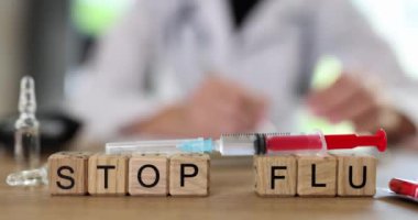 Kelimeler, şırınganın yakınındaki tahta bloklardan yapılan gribi durdurur. Masada oturan doktora karşı aşı ile. Salgın ve aşı kavramı yavaş çekim