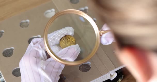 Mujer Con Guantes Protectores Mira Moneda Oro Mano Través Lupa — Vídeo de stock