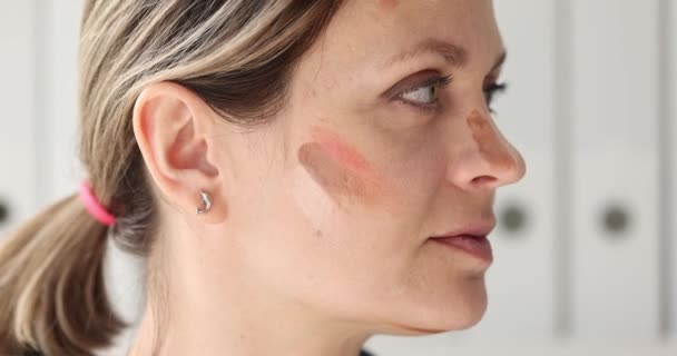 美容室で顔に異なる化粧品のサンプルを持つ集中女性 女性は肌のための基礎とブラッシャーを選択します グラマーとファッショントレンド — ストック動画