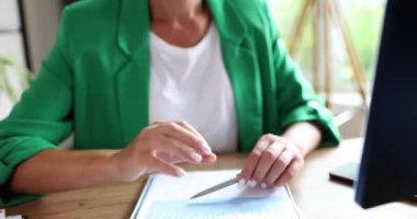 Yeşil ceketli sekreter, kâğıtların yanındaki masada 