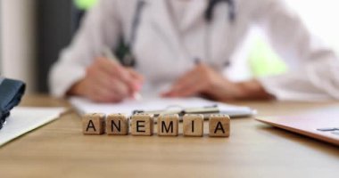 Ahşap küplere reçete yazan doktor aleyhinde Anemia yazmışlar. Klinikte harfli bloklar yavaş çekimde masada