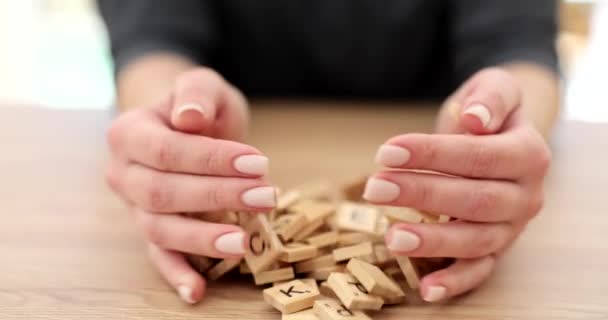 女性は英語のアルファベットで小さな木製の立方体を投げ手のひらを開きます 女性の手とテーブルの遅い動きに散乱正方形 — ストック動画