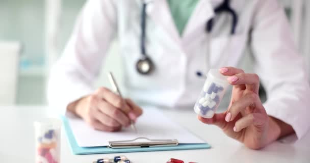セラピスト医学心臓科の医師は薬の瓶を保持し 患者に処方を書き出します 薬の選択と病気のための薬の選択 — ストック動画