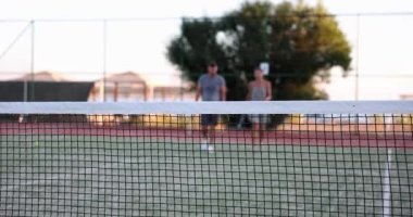 Sahada tenis oynadıktan sonra spor çifti. Tenisçi dışarıda tenis oynadıktan sonra konuşuyor ve eğleniyor.