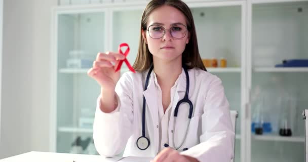 医者の女性は世界エイズデーの赤いリボンのシンボルを示しています Hivエイズは症状や治療を引き起こす — ストック動画