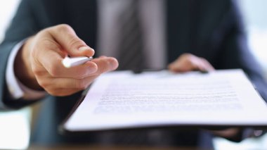 İş adamı, müşteriye yakın çekim sözleşmesi imzalaması için tükenmez kalem ve pano veriyor. Önemli kağıt konsepti sertifikası