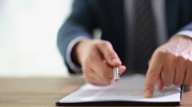 İşadamı müşteriye tükenmez kalem veriyor ve belgenin neresini imzalayacağını parmağıyla gösteriyor. İş konseptinde ortaklarla çalışmak