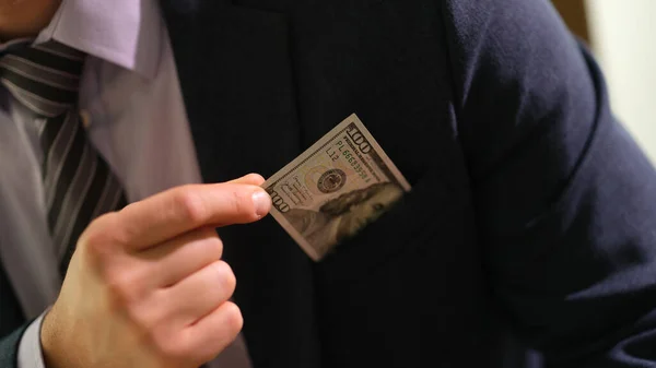 ビジネススーツのビジネスマンは ポケットの閉鎖から100ドル札を引き出す 贈収賄とブラックブックキーピングの概念 — ストック写真
