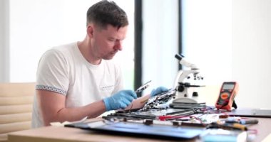 Uzman bilgisayar mühendisi büyüteçle laptop donanımını analiz ediyor. Bilgisayar ekipmanlarının onarımı ve teşhisi